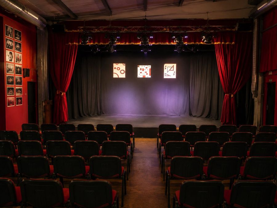 La sala allestita a teatro, con palco, sipario e platea